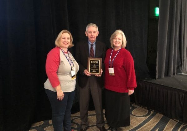 a man and two women posing with award plaque